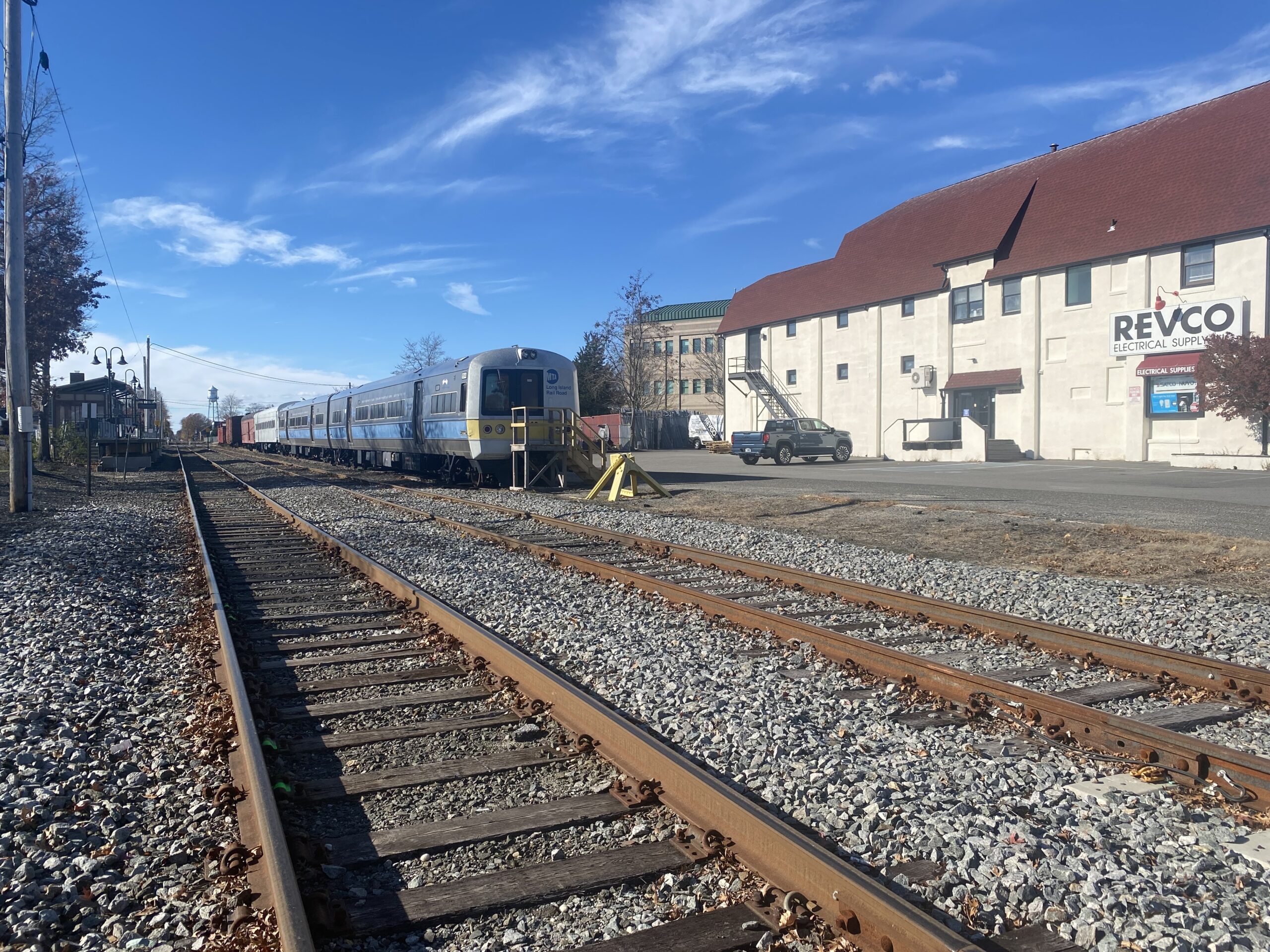 Riverhead railway's rusted-over tracks nestled in gravel, beneath a blue sky.